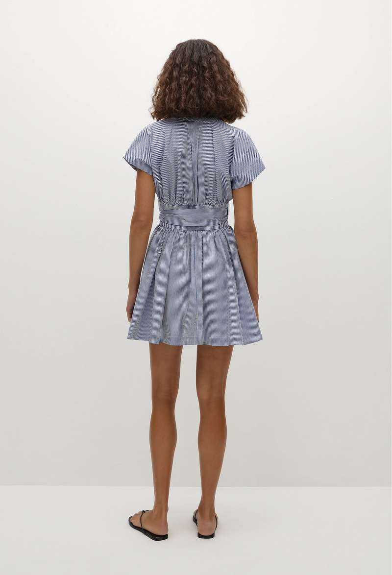 a model wearing a mini deep v-neck dress with blue and white striped and a waist tie on a white background
