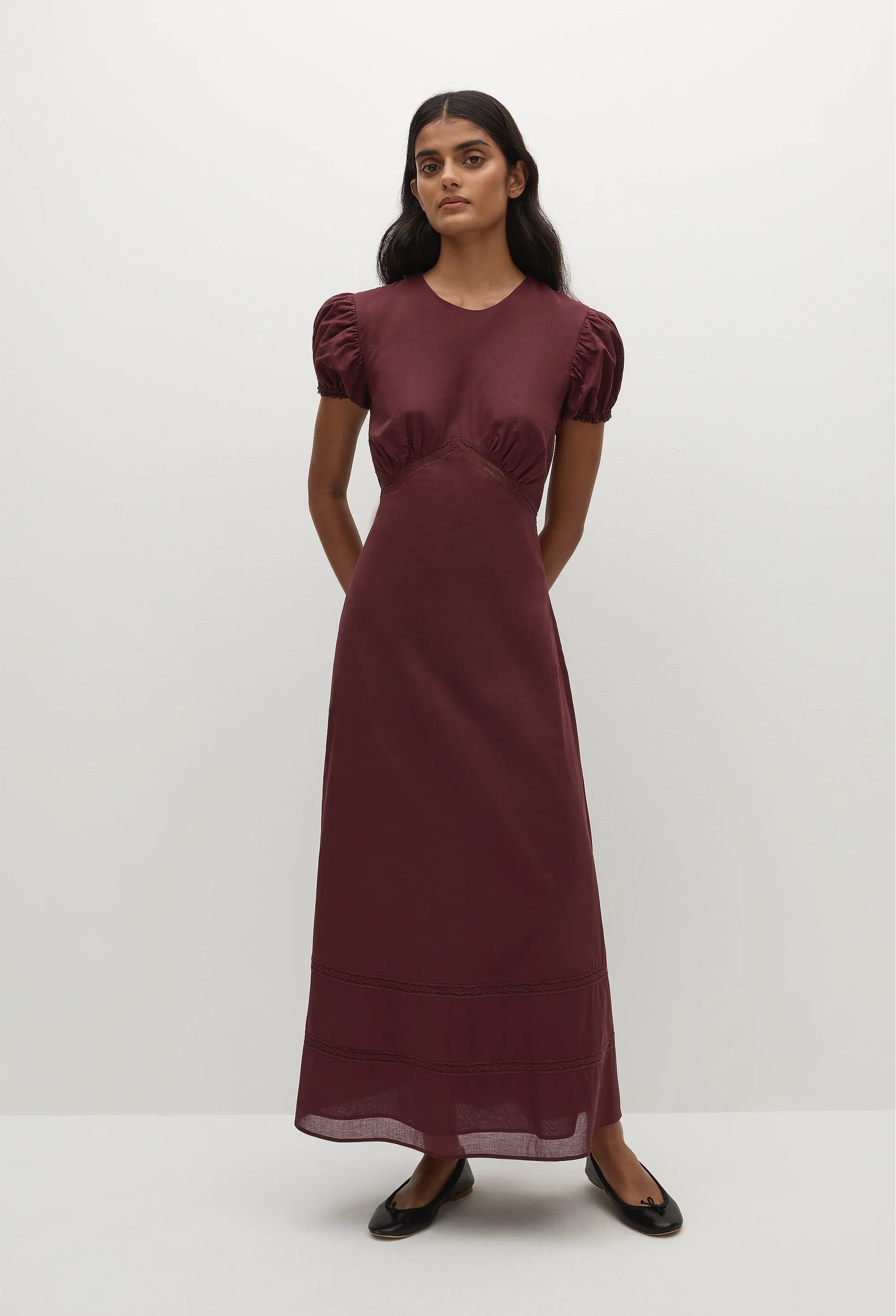 a woman wearing a midi burgundy dress with puff sleeves on a white background