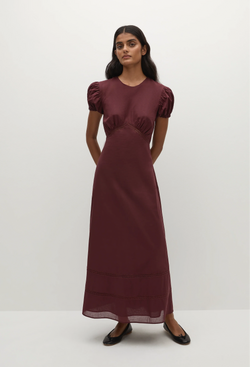a woman wearing a midi burgundy dress with puff sleeves on a white background