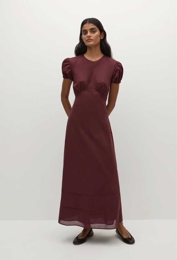 a woman wearing a midi burgundy dress with puff sleeves on a white background