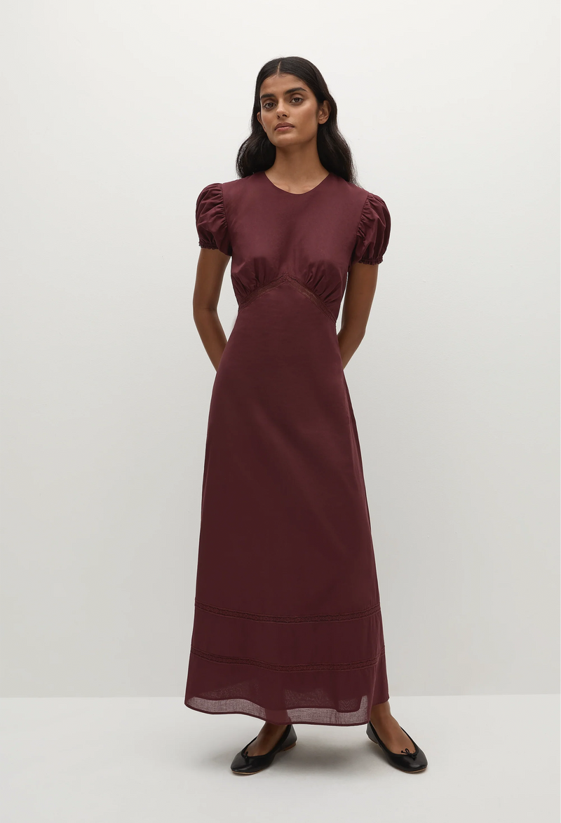 a woman wearing a midi burgundy dress with puff sleeves on a white background