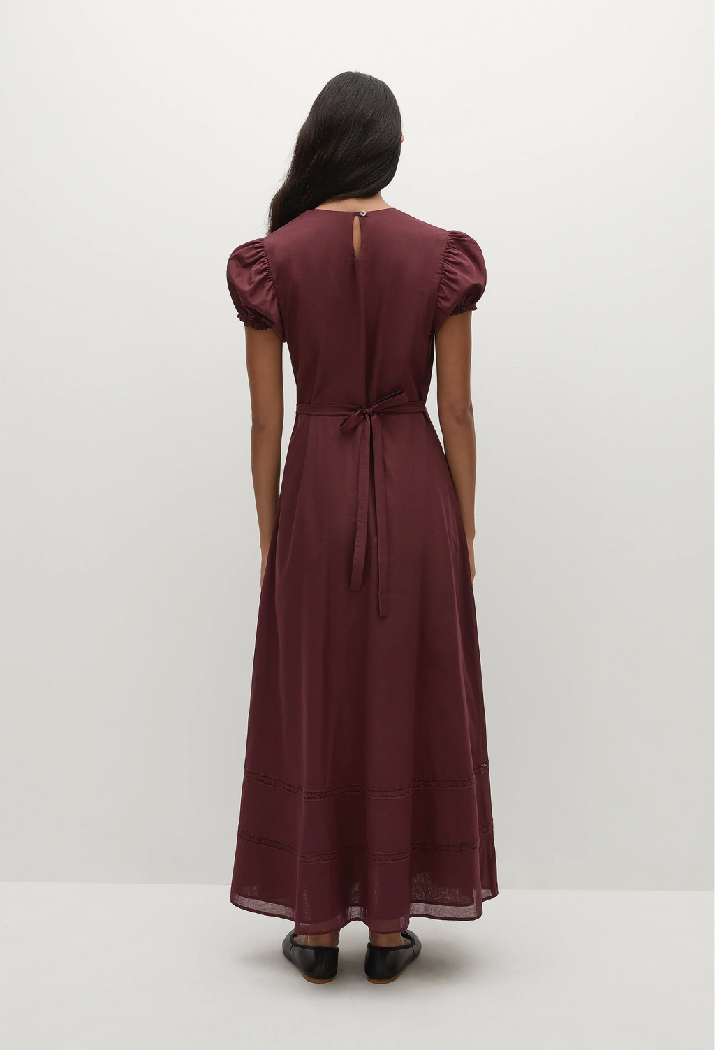 a woman wearing a midi burgundy dress with puff sleeves on a white background