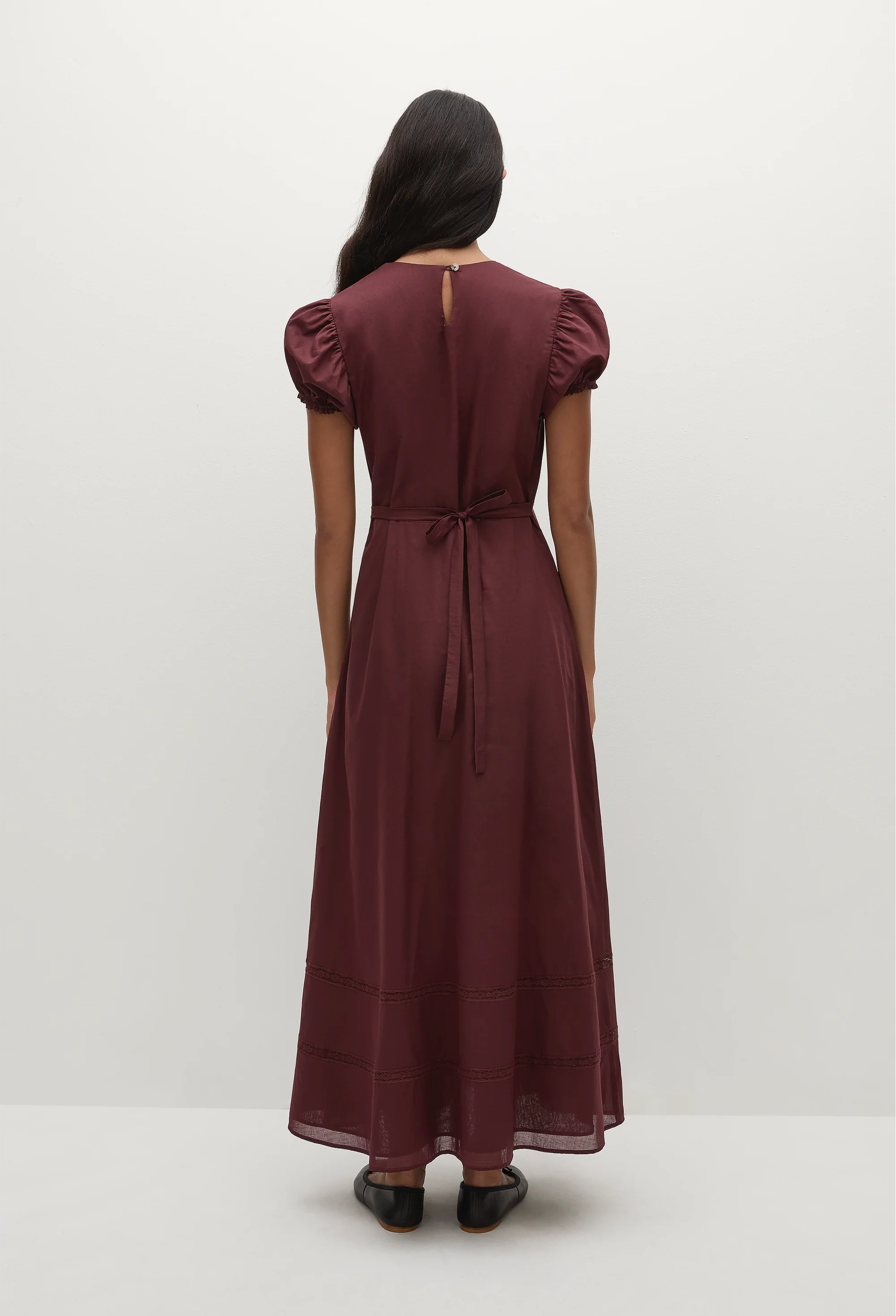 a woman wearing a midi burgundy dress with puff sleeves on a white background