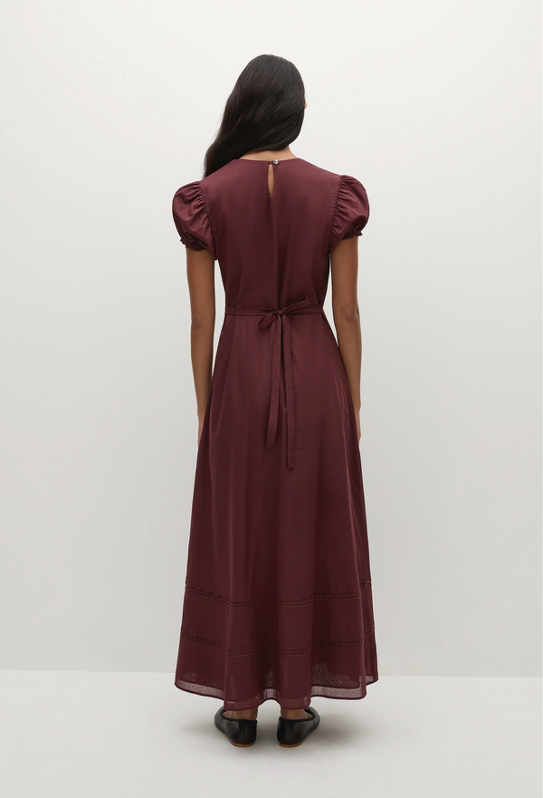 a woman wearing a midi burgundy dress with puff sleeves on a white background