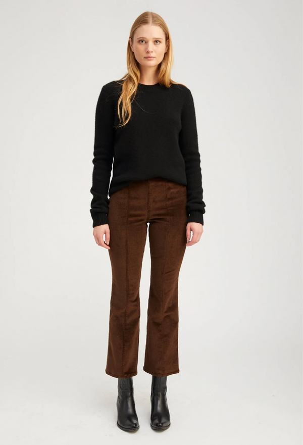 Woman wearing a black sweater and brown pants on a white background