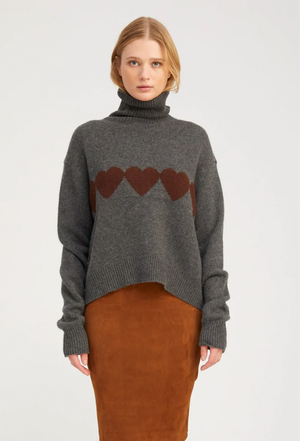 Woman wearing a gray sweater with heart designs on a white background