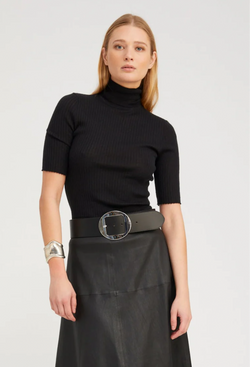 Woman wearing a black turtleneck and black skirt with a belt on a white background