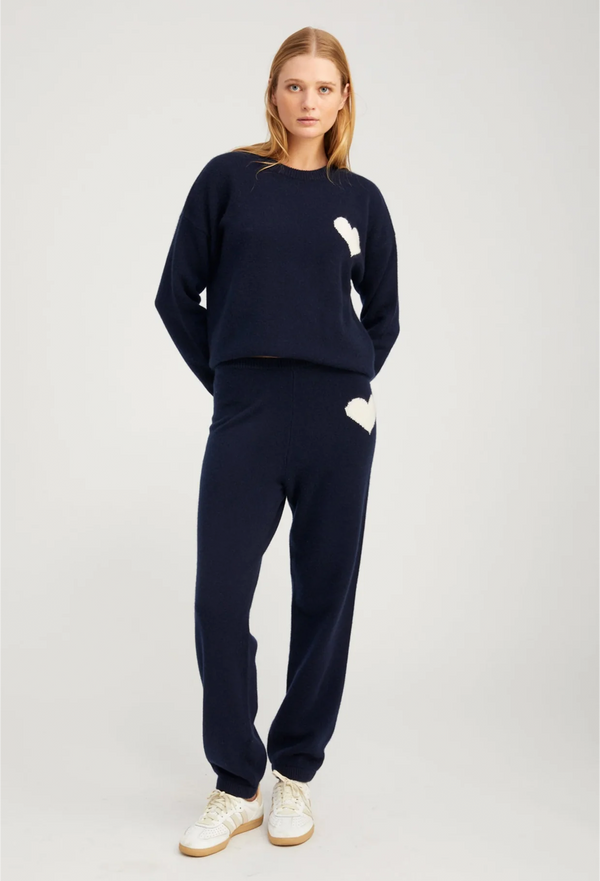 Woman wearing a navy blue outfit with white accents on a light gray background