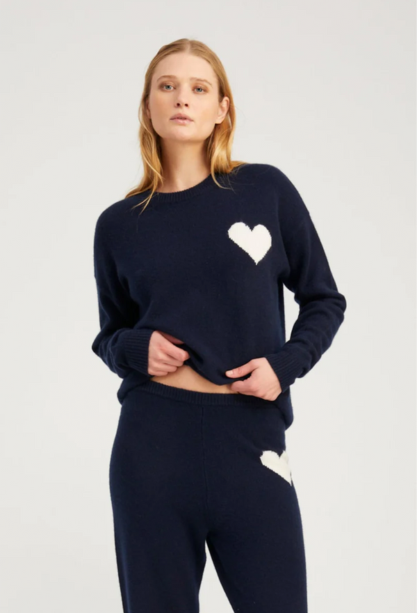 Woman wearing a navy sweater with a white heart design on a light gray background