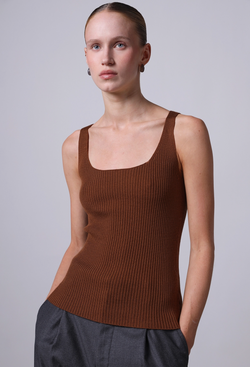 Woman wearing a brown ribbed tank top against a plain background