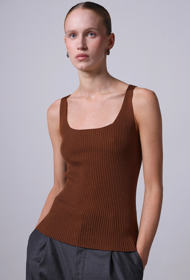 Woman wearing a brown ribbed tank top against a plain background