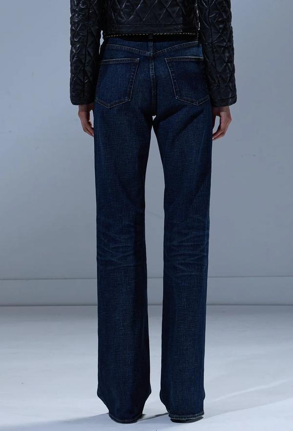 Person wearing dark blue jeans and a black jacket on a plain background