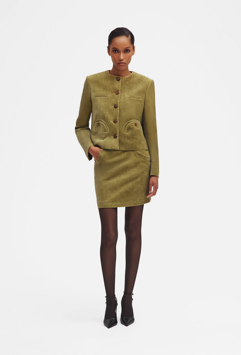 Woman wearing a green jacket and skirt with buttons on a white background
