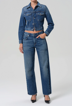 Person wearing a blue denim jacket and jeans on a white background