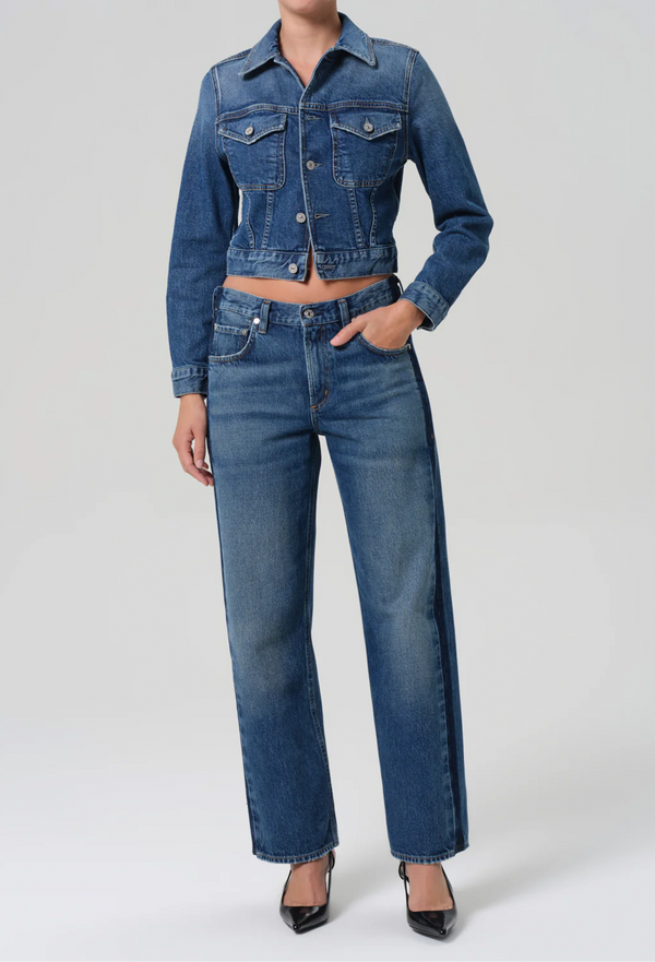 Person wearing a blue denim jacket and jeans on a white background