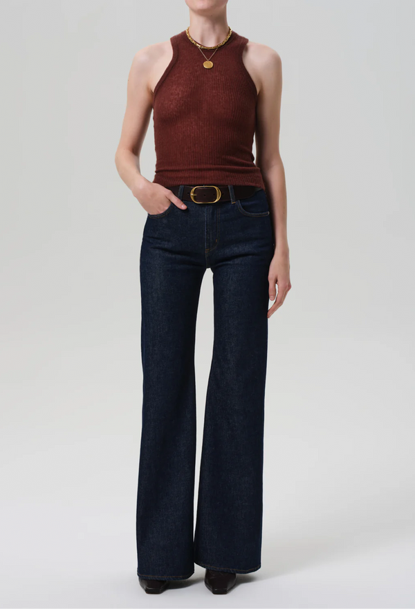 Person wearing a brown sleeveless top and dark blue jeans on a white background