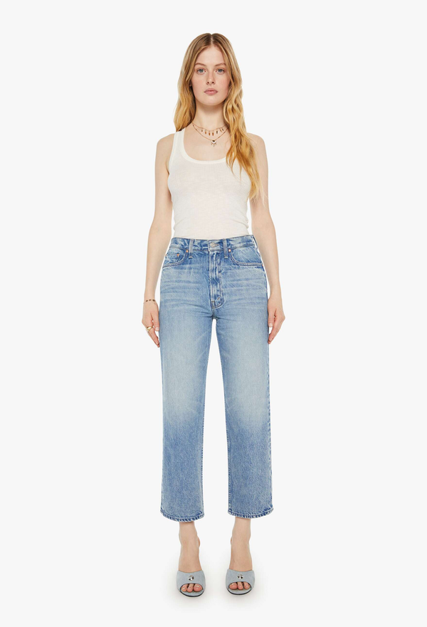 Woman wearing a white tank top and light blue jeans on a white background