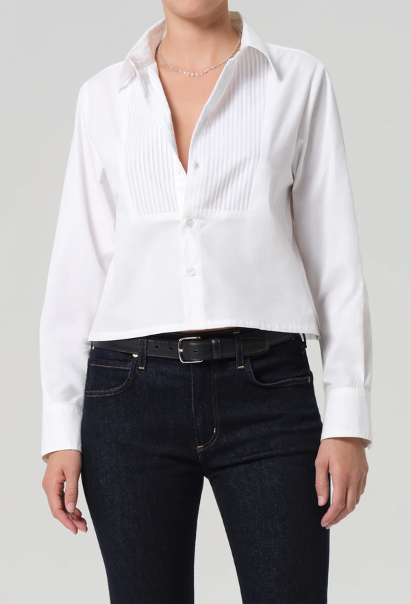 Person wearing a white button-up shirt and black pants on a plain background