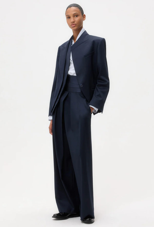 Person wearing a navy suit with a white shirt on a white background
