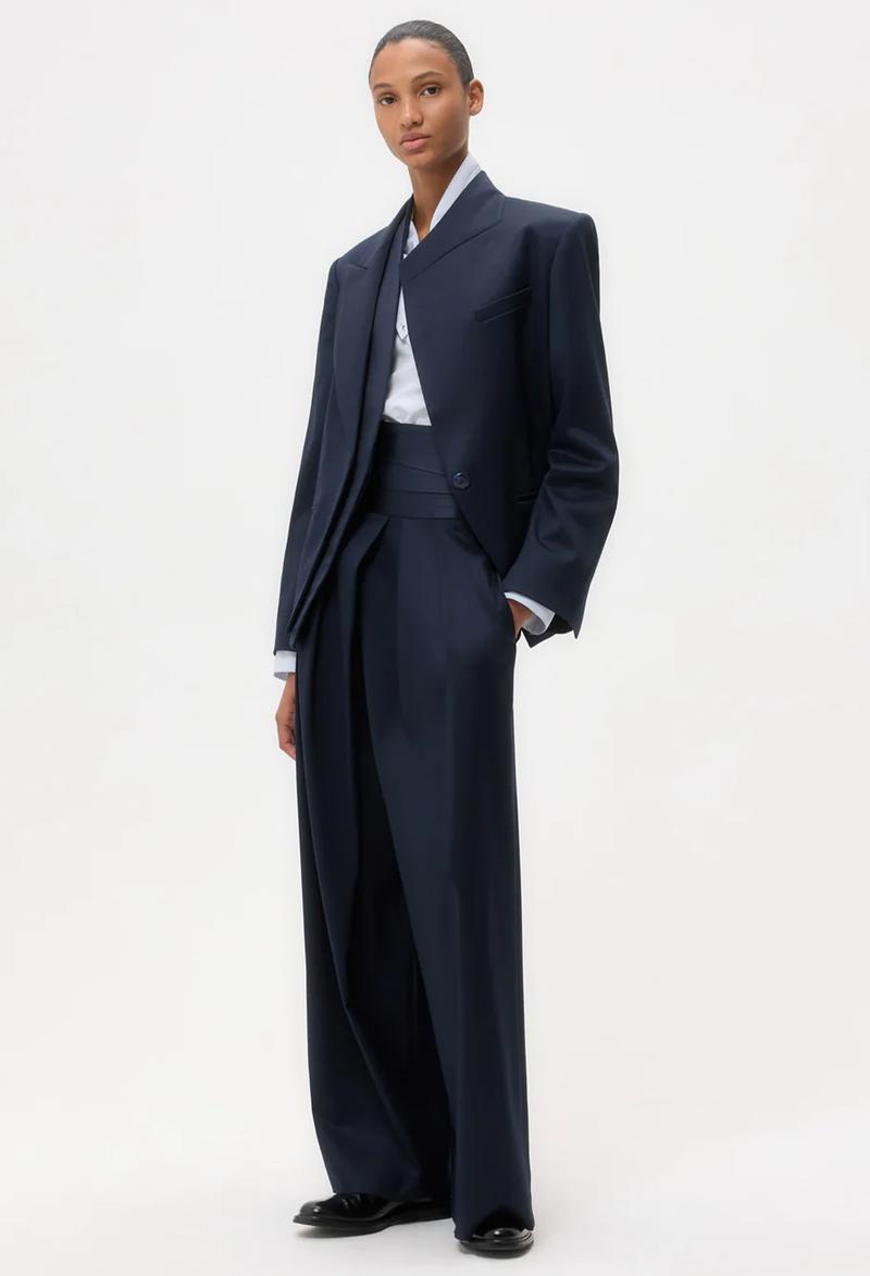 Person wearing a navy suit with a white shirt on a white background