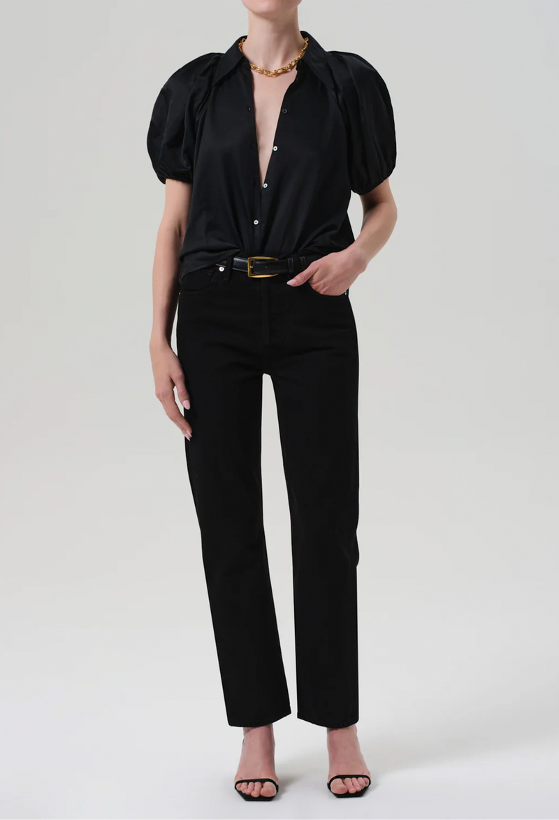 Person wearing a black top and jeans with a belt on a white background