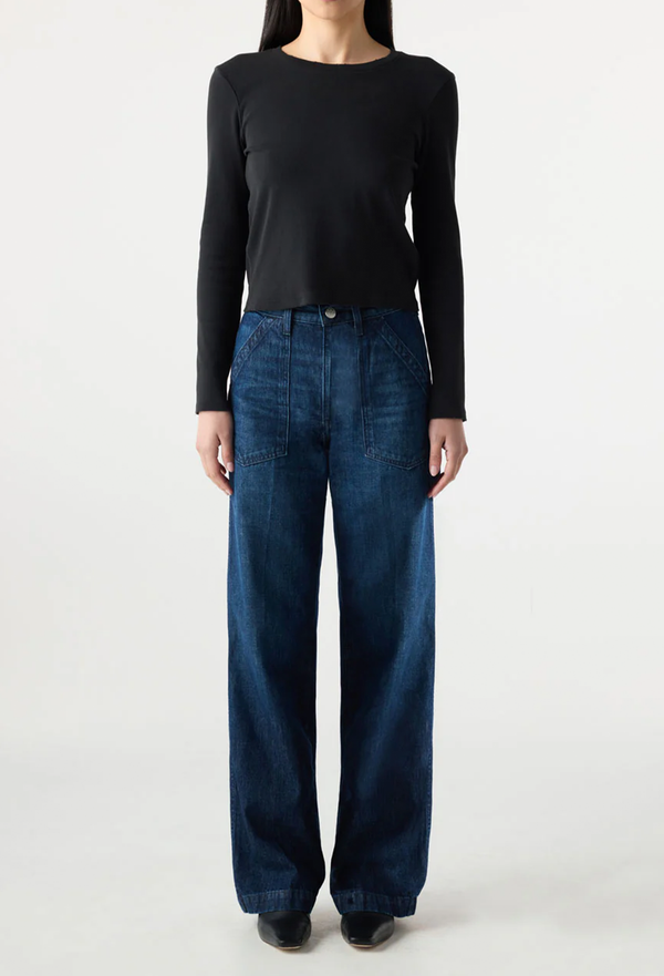 Person wearing a black long-sleeve top and blue jeans on a white background