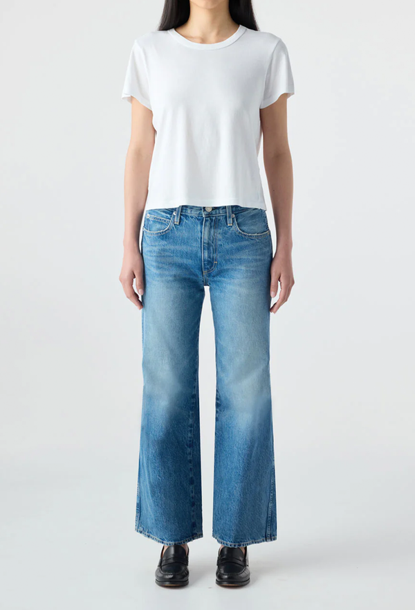Person wearing a white t-shirt and blue jeans on a plain background