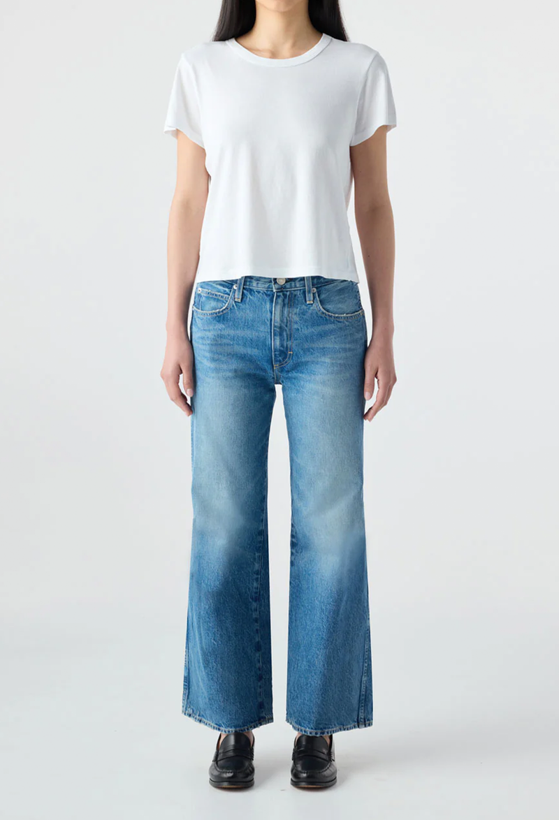 Person wearing a white t-shirt and blue jeans on a plain background