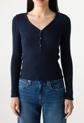 Person wearing a navy ribbed long-sleeve henley shirt and blue jeans on a white background