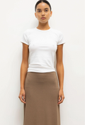 Person wearing a white t-shirt and brown skirt on a plain background