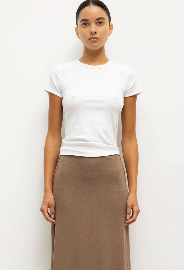 Person wearing a white t-shirt and brown skirt on a plain background