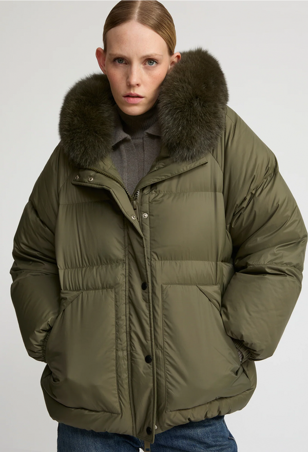 Person wearing a green puffer jacket with a fur-lined hood on a white background