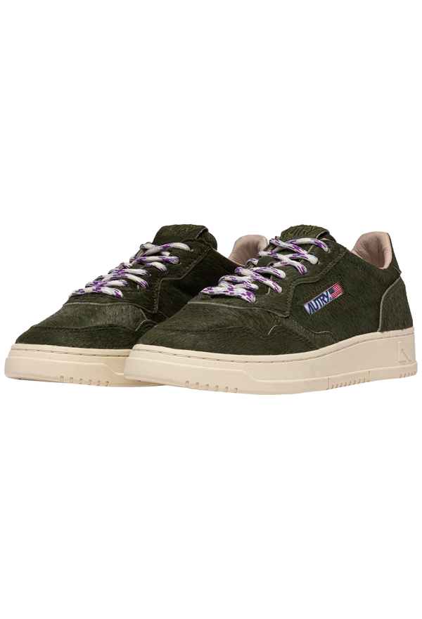 Green sneakers with purple laces on a white background