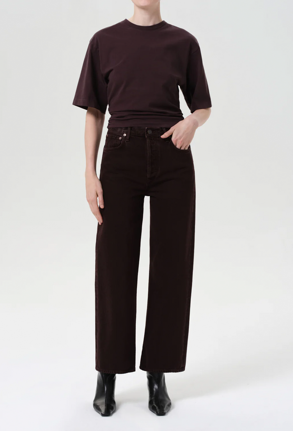 Person wearing a dark brown t-shirt and dark purple/brown wide-leg jeans on a white background