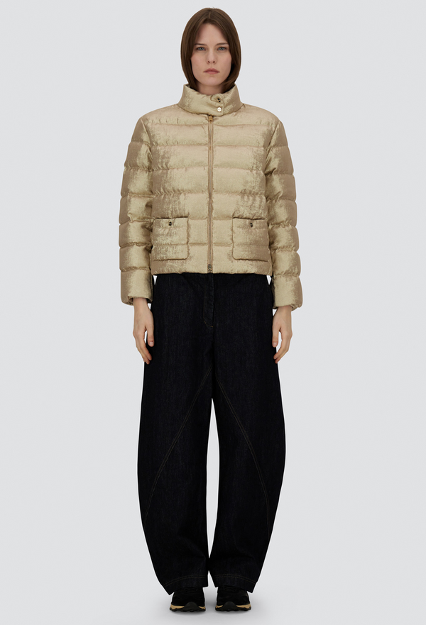 Person wearing a beige puffer jacket and black pants on a white background