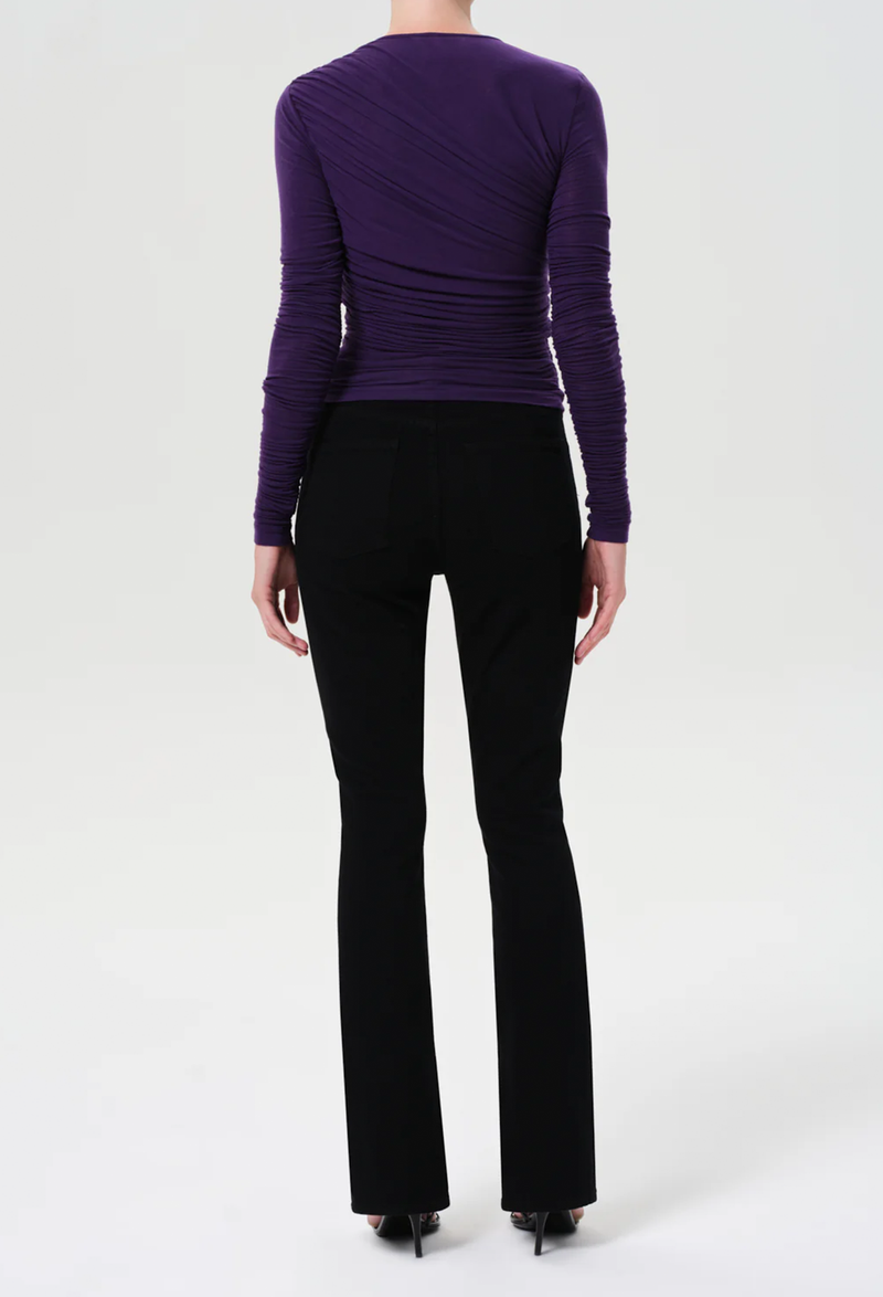 Person wearing a purple long-sleeve top and black pants on a white background