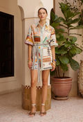 Woman wearing a colorful patterned dress standing in a decorative interior setting with plants.