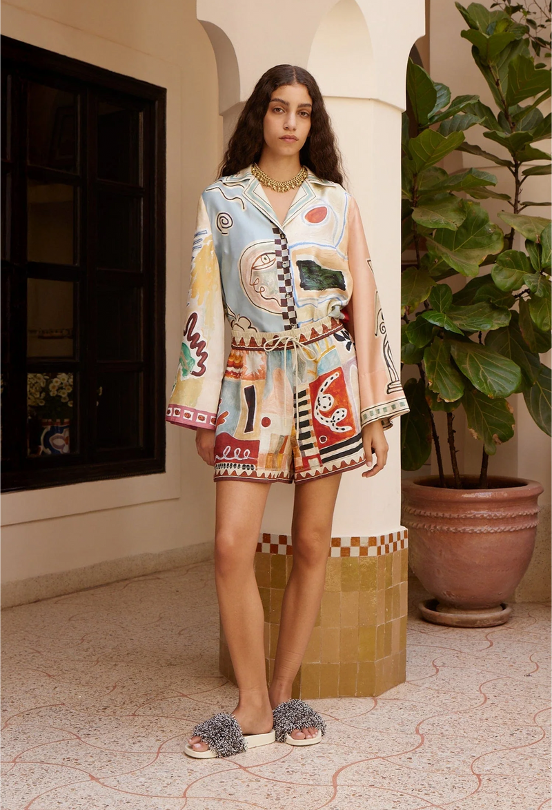 Woman wearing a colorful outfit standing in a decorative interior setting with plants