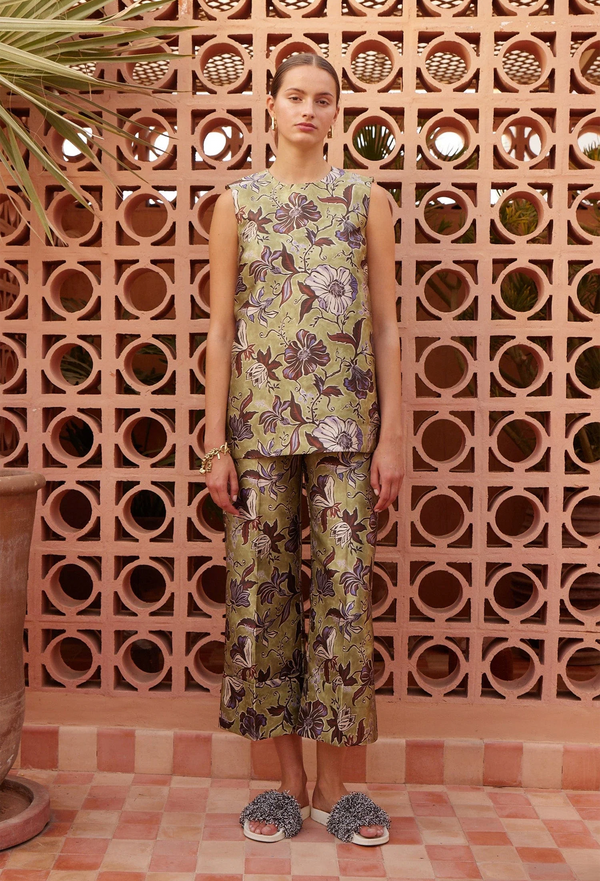Woman wearing a floral outfit standing in front of a decorative wall with a checkered floor.