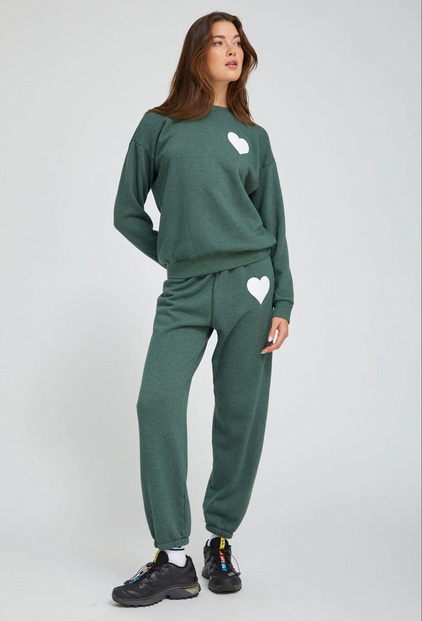 Person wearing a green sweat set with heart designs on a white background