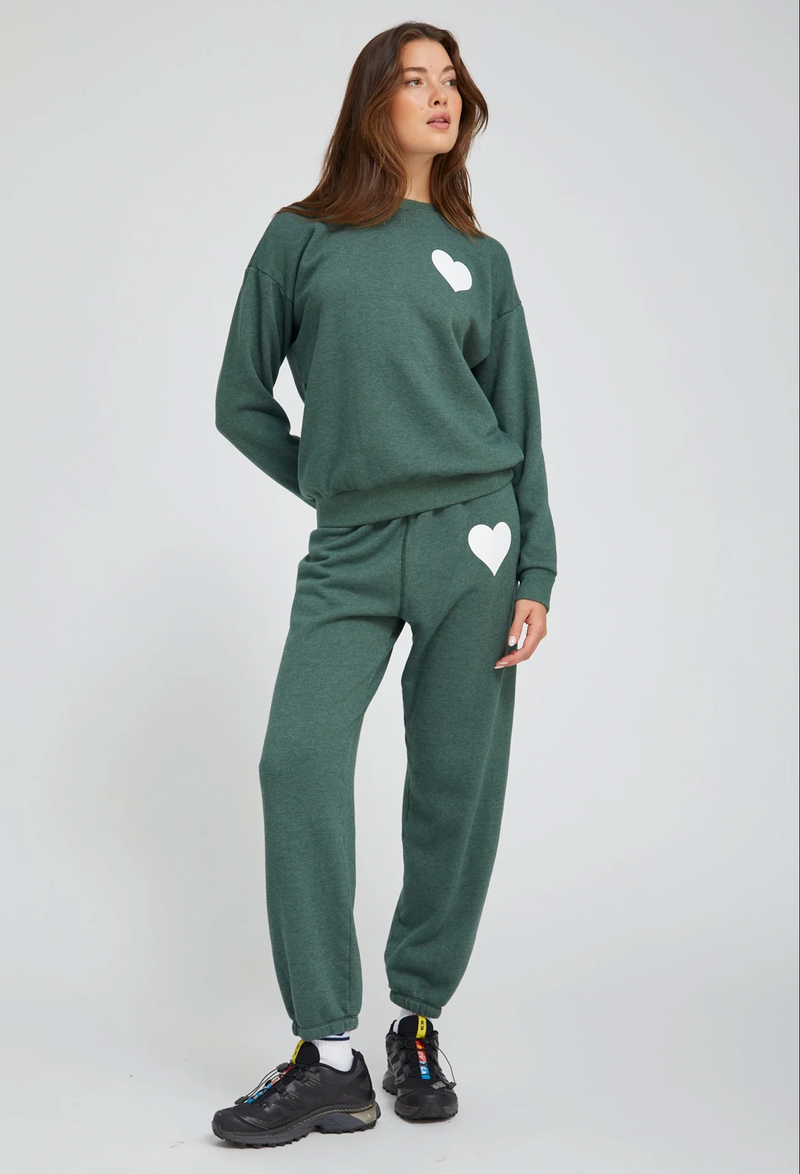 Person wearing a green sweat set with heart designs on a white background