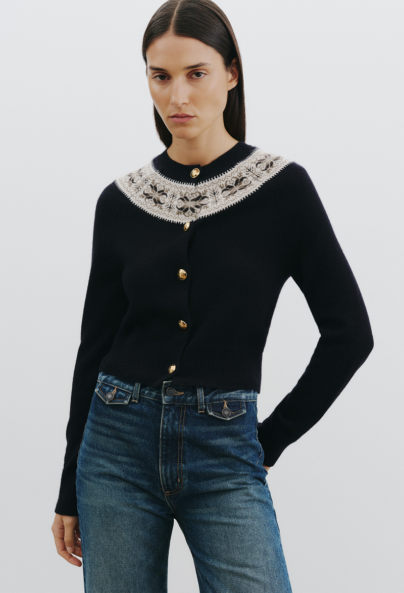 a woman wearing a dark navy fair isle cardigan and jeans on a white background