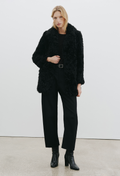 a woman wearing a black coat and black pants on a white background