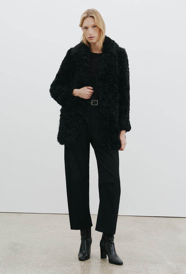 a woman wearing a black coat and black pants on a white background