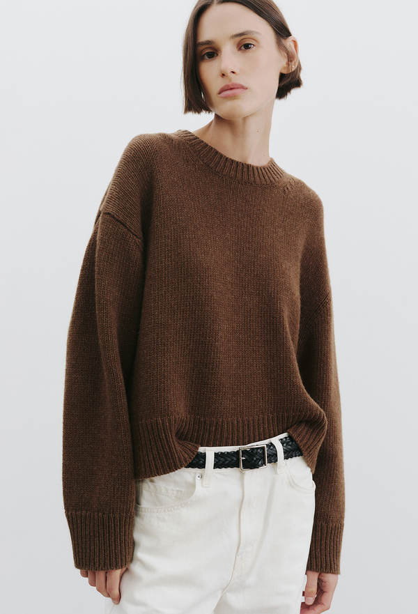 woman wearing a brown sweater and jeans on a white background