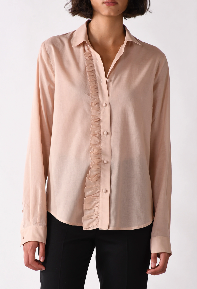 Woman wearing a light pink blouse with ruffle details on a white background