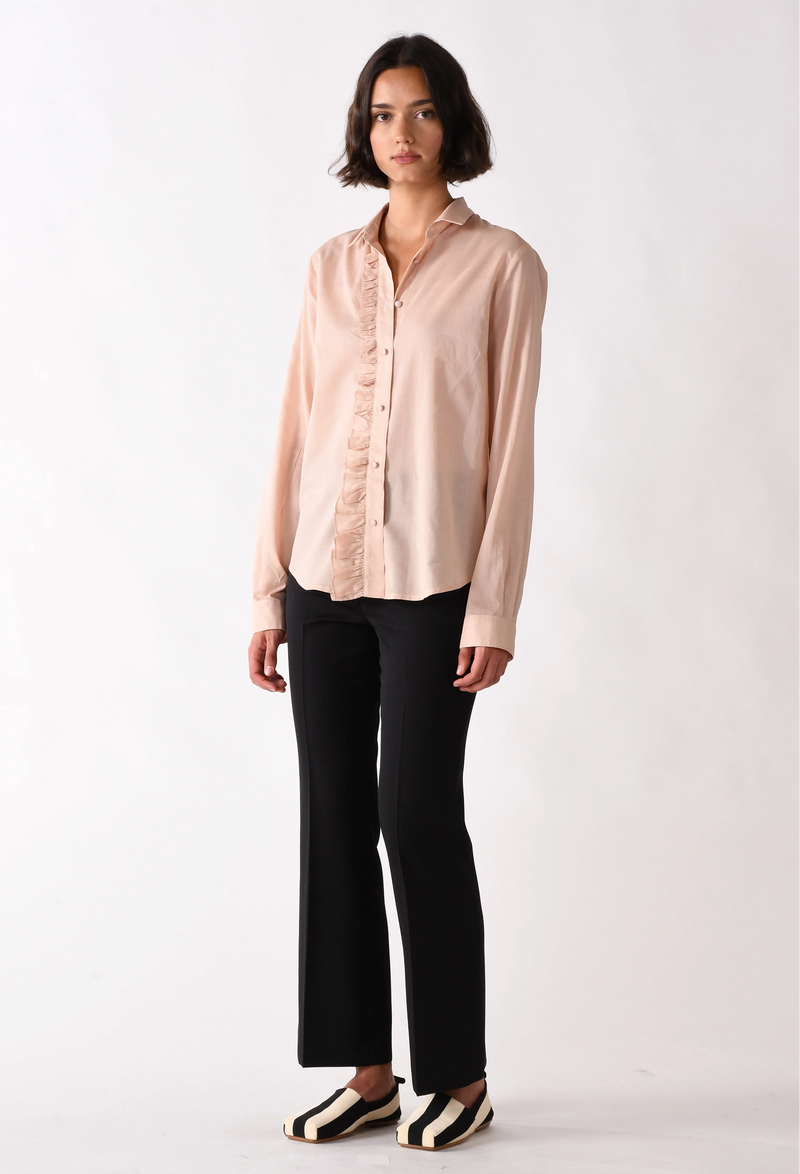 Woman wearing a light pink blouse and black pants on a white background