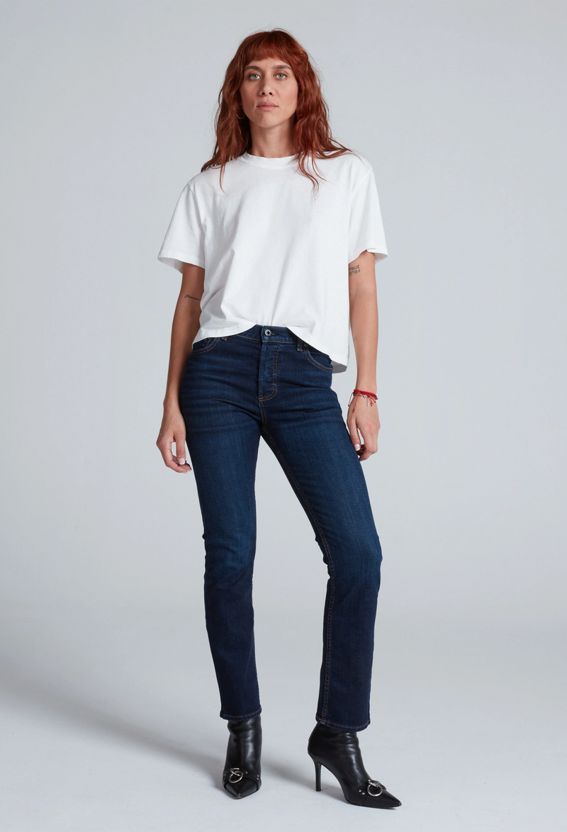 Woman wearing a white t-shirt and blue jeans on a plain background