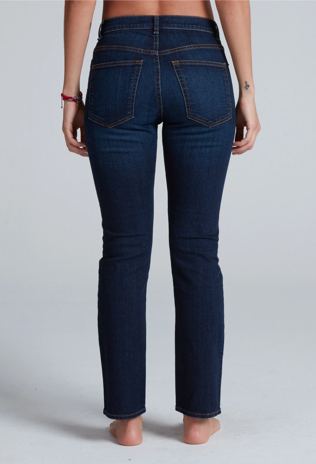 Person wearing dark blue jeans on a plain background