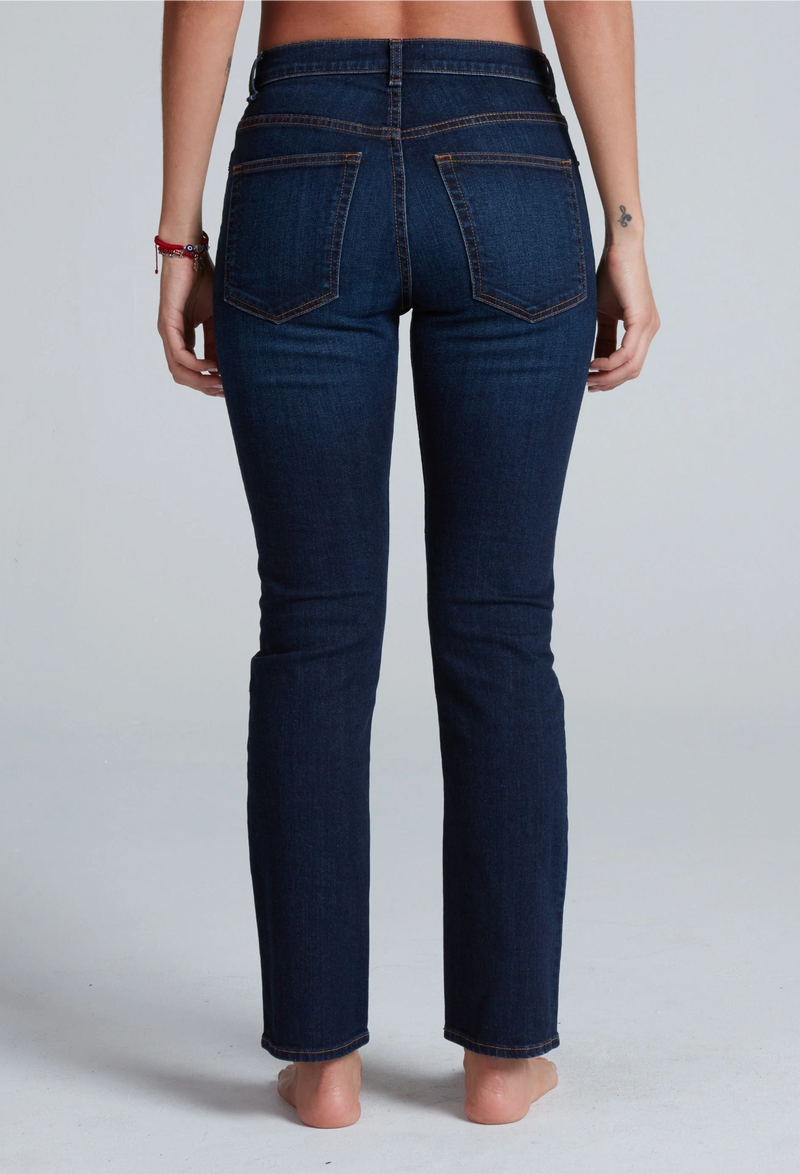 Person wearing dark blue jeans on a plain background